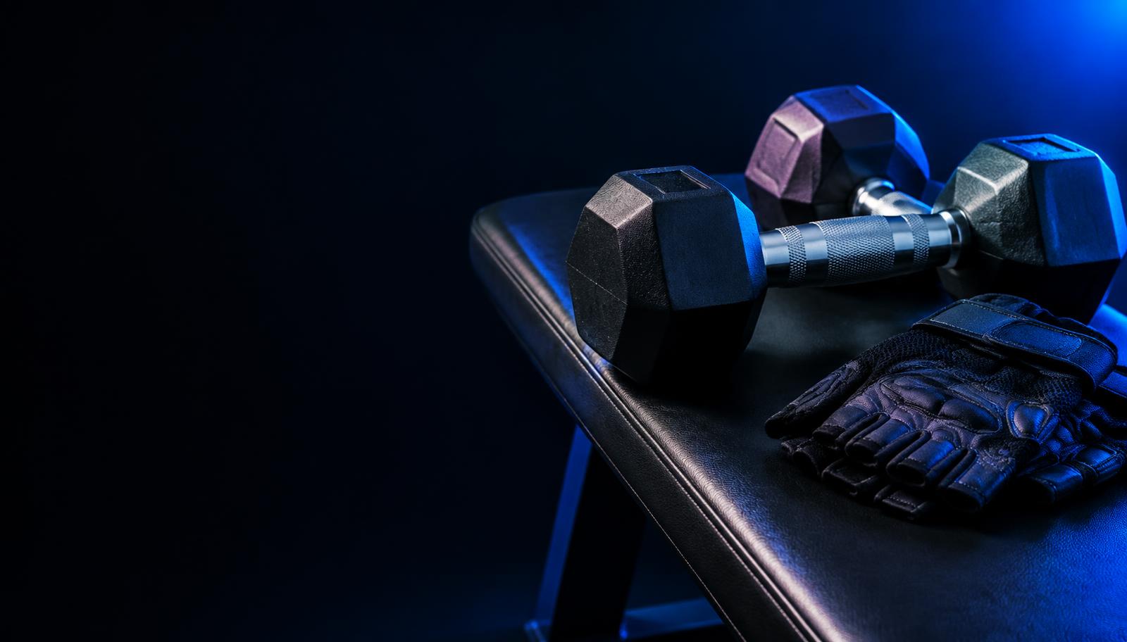 Dumbbells and training gloves in blue light